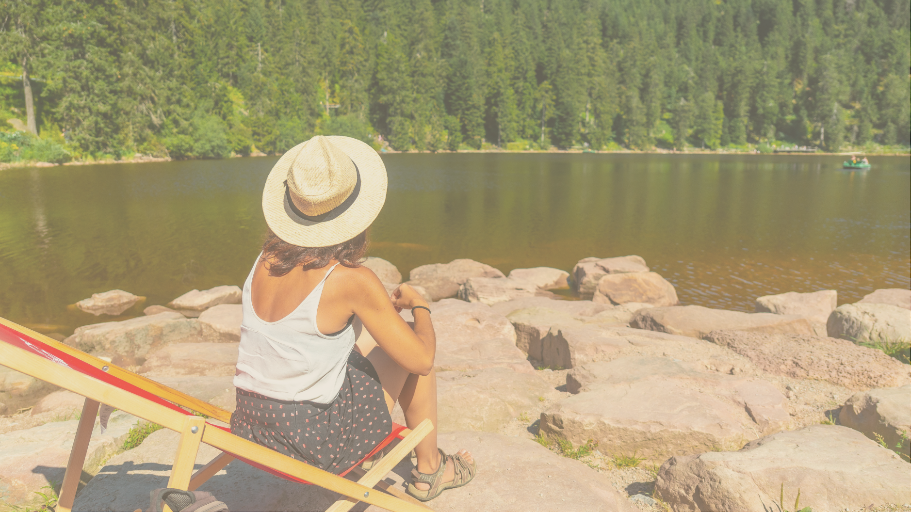 A woman relaxing on rocks by a scenic river during a luxury RV vacation, enjoying upscale amenities and off-grid comfort.